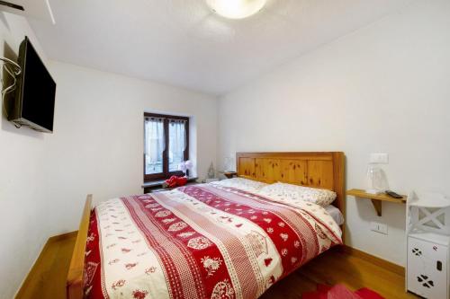 a bedroom with a bed with a red and white blanket at L'archetto Valle d'Aosta in La Salle