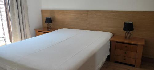 a bedroom with a white bed with two night stands at Apartamento Sol e Mar 1 in Monte Gordo