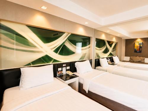 a hotel room with two beds and a couch at Nova Platinum Hotel in Pattaya South