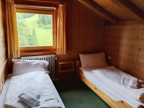 two beds in a room with a window at Rifugio Plan Boè in Livinallongo del Col di Lana