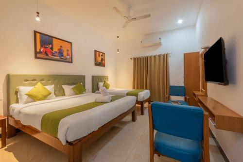 a bedroom with two beds and a flat screen tv at De Asian Resort in Pondicherry