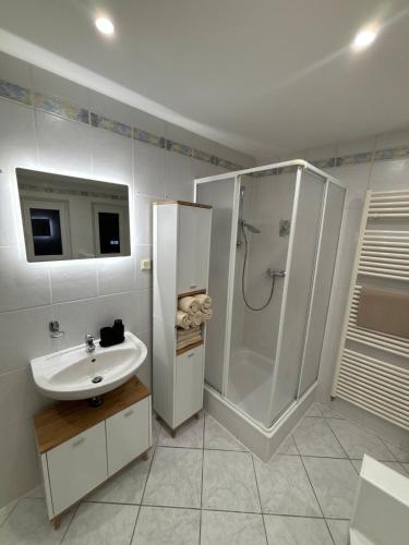 a white bathroom with a sink and a shower at Ferienwohnung Noela in Sankt Ingbert