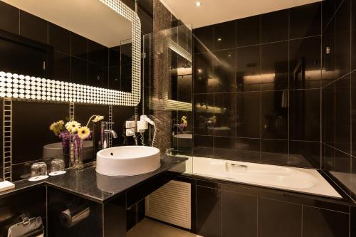 a black bathroom with a sink and a mirror at Nova Platinum Hotel in Pattaya South