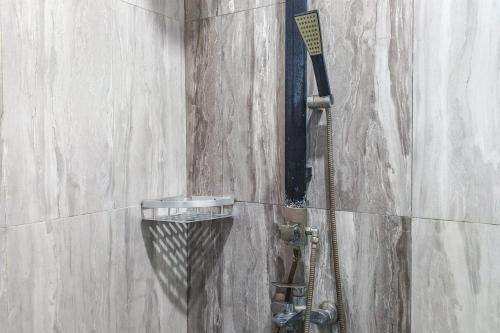 a shower with a shower head on a wall at Dprof Exclusive Guesthouse Semarang RedPartner in Jatingaleh