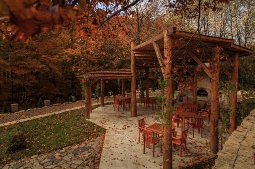 a wooden pavilion with tables and chairs in a park at Cetatuia in Măgura