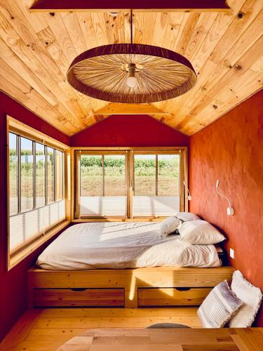 a bed in a room with a large window at Tiny House en lisière de bois in Bastennes