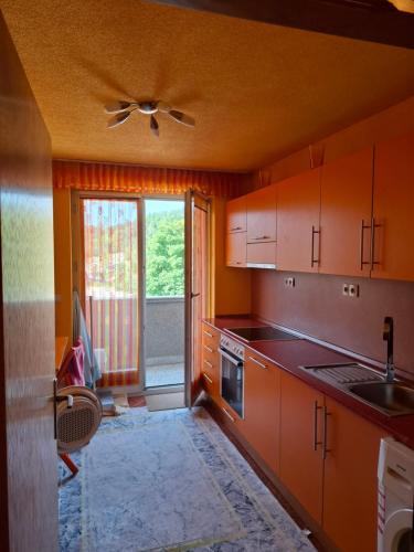 a kitchen with wooden cabinets and a ceiling fan at Apartman National 2 in Velika Kladuša