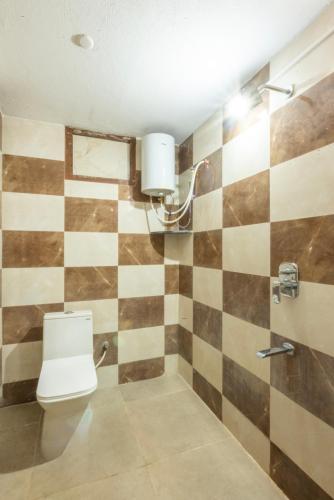 a bathroom with a toilet and a checkerboard wall at De Asian Resort in Pondicherry