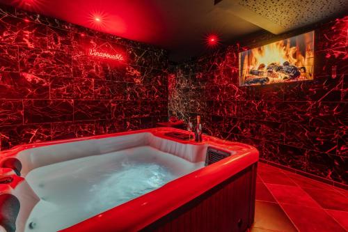 a red bathroom with a tub with a fire in it at L'inavouable Love-room Jacuzzi in Marquise
