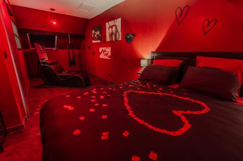 a red bedroom with a bed with hearts on it at L'inavouable Love-room Jacuzzi in Marquise