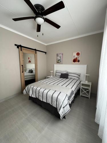 a bedroom with a bed with a ceiling fan at Oceanview Stays in Great Brak River