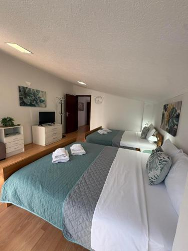 a bedroom with two beds and a flat screen tv at SIENA Apartment in Gevgelija
