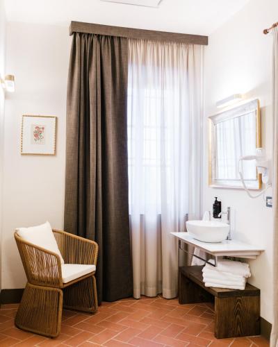 a bathroom with a sink and a chair and a mirror at Villa Castiglione in Impruneta