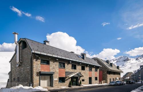 a large brick building with mountains in the background at Estival Caribou in Pas de la Casa
