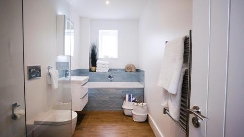 a white bathroom with a sink and a toilet at La Pulente Cottages in St. Brelade