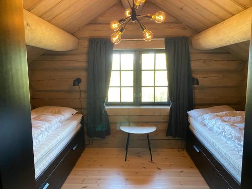 a bedroom with two beds and a table and a window at Koslig helårs hytte in Heimdal