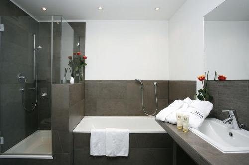 a bathroom with a tub and a sink and a shower at Hotel Regina in Cologne