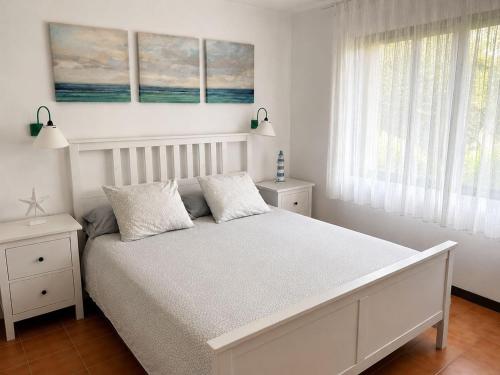 ein weißes Schlafzimmer mit einem Bett und zwei Fenstern in der Unterkunft Mas Mato, 25, 3B in Begur