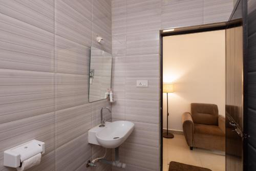 a bathroom with a sink and a mirror and a chair at Palolem White House in Canacona
