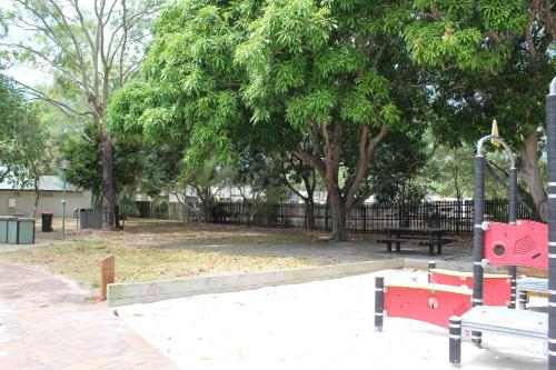 a park with a red bench and a swing at Mango Tree Motel in Agnes Water