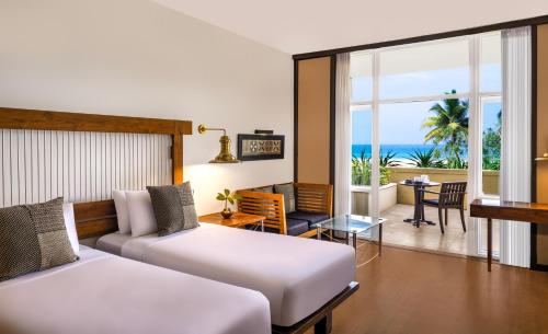 two beds in a room with a view of the ocean at Heritance Ahungalla in Ahungalla
