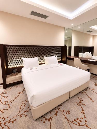 a bedroom with a large white bed and a desk at Ayan Hotel in Riyadh
