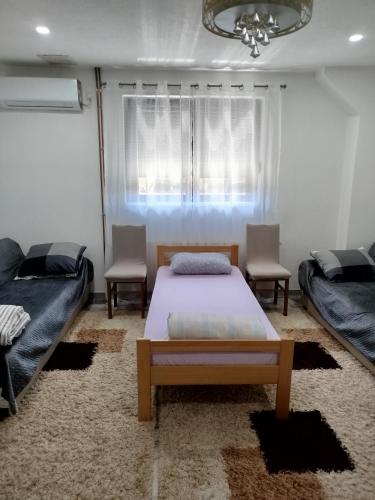 a bedroom with a bed and two chairs and a window at Avdic Guest House in Makljenovac