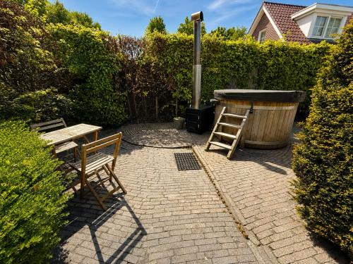 a patio with a table and two chairs and a grill at The Cosy Cottage - Comfort Sauna & Hot Tub in Private Garden in Zeewolde