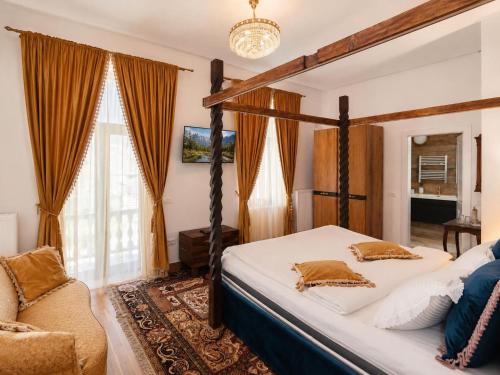 a bedroom with a four poster bed and a chair at Queen's Crown Manor in Predeal
