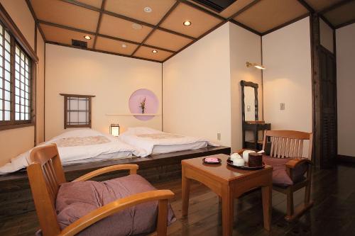 a room with two beds and a table and chairs at Ryokan Yamanoyu in Minamioguni