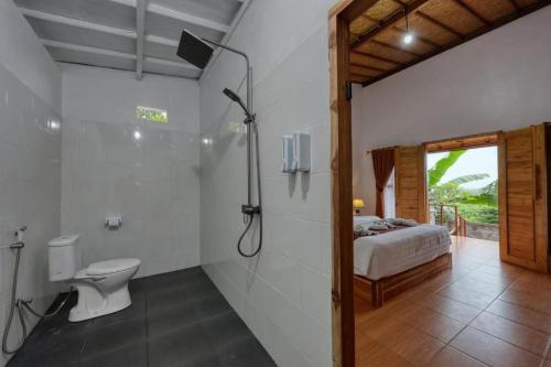 a bathroom with a shower and a toilet and a bed at The Penida Angmas View in Nusa Penida
