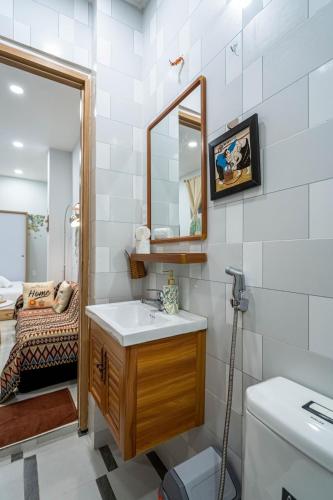 a bathroom with a sink and a mirror and a toilet at LalaHouse Pasteur in Ho Chi Minh City