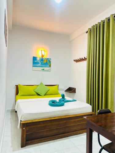 a bedroom with a bed with yellow and green curtains at Jaya Villa - Near Airport in Negombo