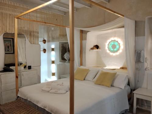 a bedroom with a canopy bed with white sheets and yellow pillows at B&B "Pulia Dimore Salentine" in Alessano