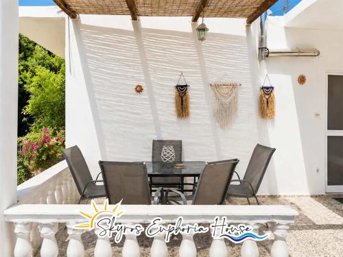 a table and chairs on a patio with a white wall at Skyros Euphoria House in Skiros