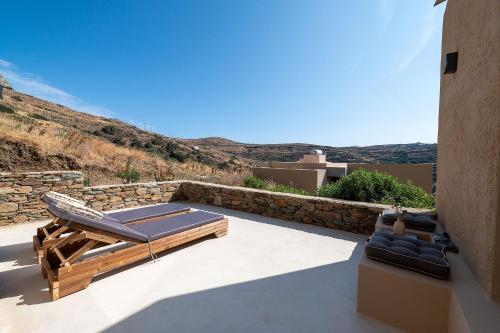 a patio with two chaise lounges and a rock wall at The Aer Element Of Gaea in Loutrá