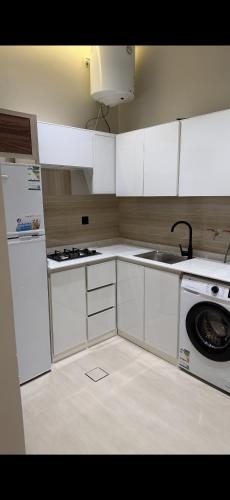 a kitchen with white cabinets and a sink and a dishwasher at Elite Stay in Buraydah