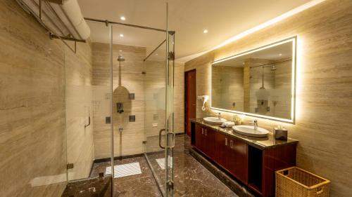 a bathroom with two sinks and a glass shower at KK Royal Hotel & Convention Centre in Jaipur