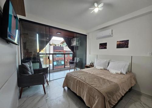 a bedroom with a bed and a chair and a window at Studio moderno no centro próximo a Academia e Cave in Juiz de Fora
