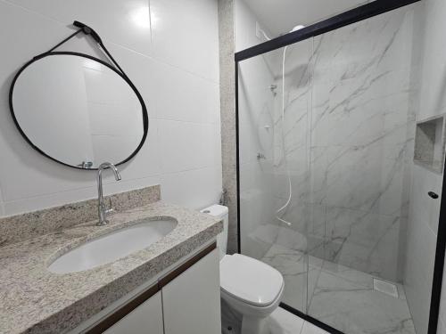 a bathroom with a sink and a mirror and a toilet at Studio moderno no centro próximo a Academia e Cave in Juiz de Fora