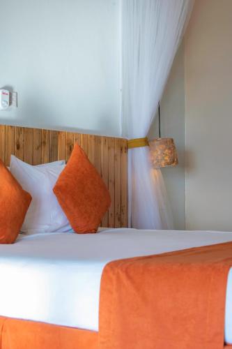 a bedroom with a bed with orange and white pillows at Acacia Wilderness Mweya in Kasese
