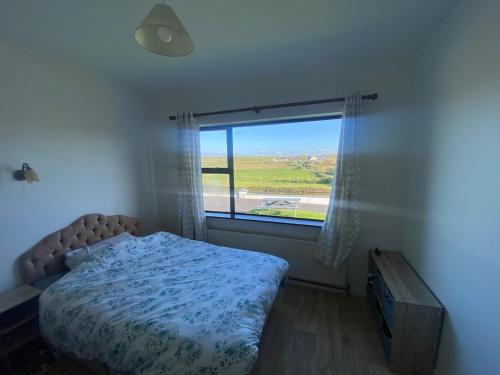 a bedroom with a bed and a large window at Farrihy Hill House in Doonbeg