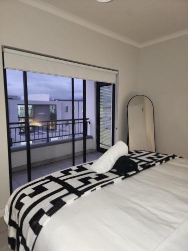 a bedroom with a large bed with a view of a balcony at Summer Set West in Somerset West
