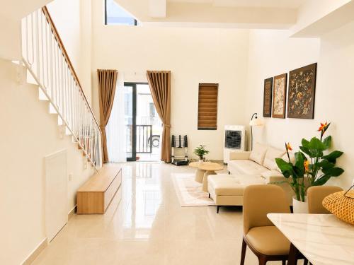 a living room with white furniture and a staircase at VSIP Executive Living in Hòa Lợi (1)