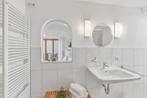 a white bathroom with a sink and a mirror at Scharnhäusle 6 - wunderschönes Apartment mit Balkon in Ostfildern