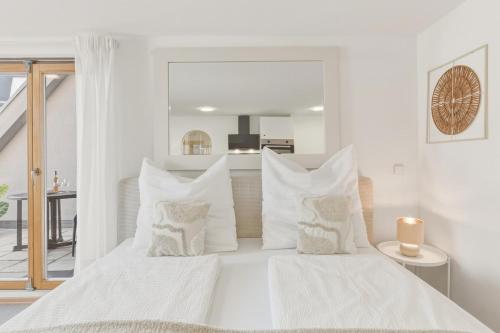 a white bedroom with two beds with white pillows at Scharnhäusle 6 - wunderschönes Apartment mit Balkon in Ostfildern