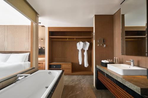 a bathroom with a tub and a bed and a sink at Mövenpick Villas & Residences Phu Quoc in Phú Quốc