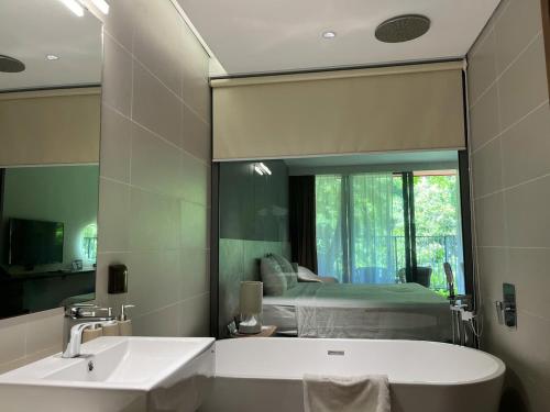 a bathroom with a mirror and a tub and a bed at Flamingos Cat Ba pre núi in Cat Ba