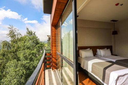 a bedroom with a bed on a balcony at Lens Design Hotel in Kazbegi