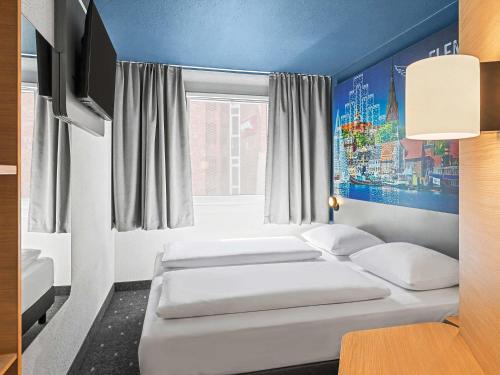 a room with two beds and a window at B&B HOTEL Flensburg-City in Flensburg